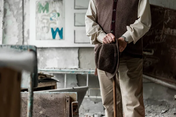 Cropped view of senior man holding hat while standing with walking cane — Stock Photo