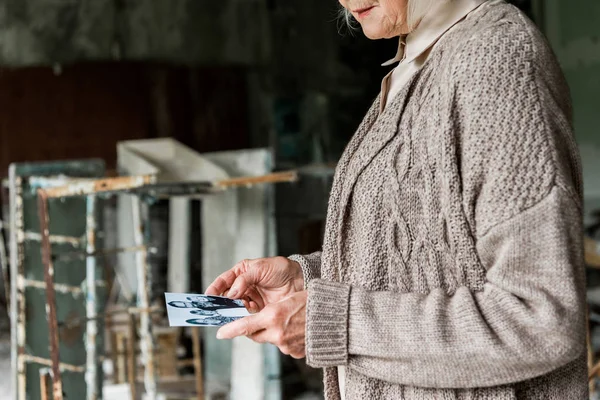 PRIPYAT, UCRAINA - 15 AGOSTO 2019: vista ritagliata della donna anziana con foto in bianco e nero — Foto stock