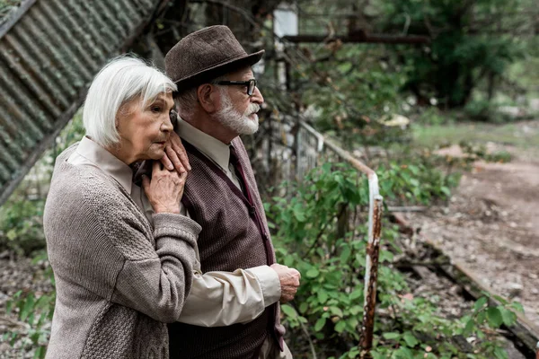 Seniorin steht und rührt Rentner mit Hut an — Stockfoto