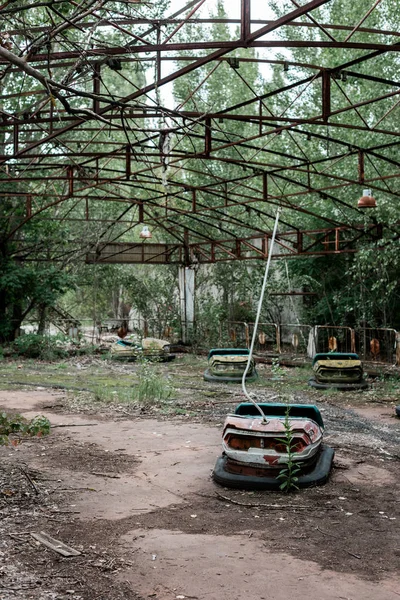 PRIPYAT, UKRAINE - AGOSTO 15, 2019: carros-pára-choques no parque de diversões abandonado perto de árvores — Fotografia de Stock