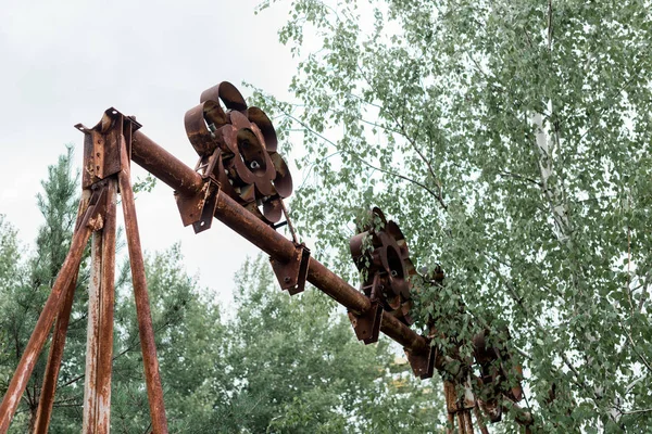 ПРИПЯТ, УКРАИНА - 15 августа 2019 года: низкоугловой вид на деревья вблизи металлического строительства в парке — стоковое фото
