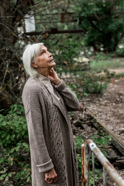 Senior woman with grey hair standing in abandoned park in chernobyl — Stock Photo