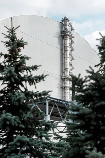 PRIPYAT, UCRÂNIA - AGOSTO 15, 2019: foco seletivo de reator de chernobyl abandonado perto de pinheiros verdes — Fotografia de Stock