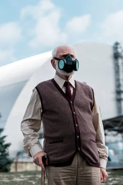 PRIPYAT, UCRAINA - 15 AGOSTO 2019: uomo anziano in maschera protettiva in piedi vicino al reattore di Chernobyl abbandonato — Foto stock