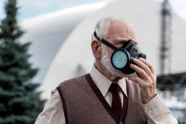 Pripjat, Ukraine - 15. August 2019: Senior Mann berührt Schutzmaske in der Nähe des stillgelegten Reaktors Tschernobyl — Stockfoto