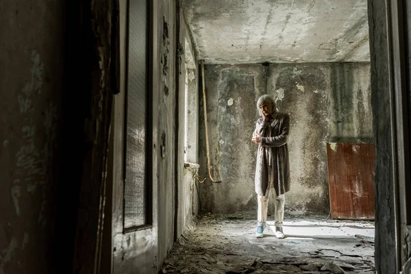 Triste femme âgée debout dans la chambre vide et sale — Photo de stock