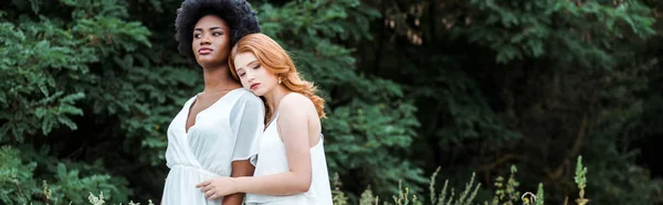 Panoramic shot of redhead girl hugging african american friend outside — Stock Photo