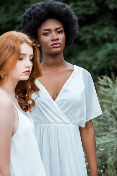 Селективный фокус привлекательной африканской американской девушки, стоящей рядом с рыжей женщиной — стоковое фото