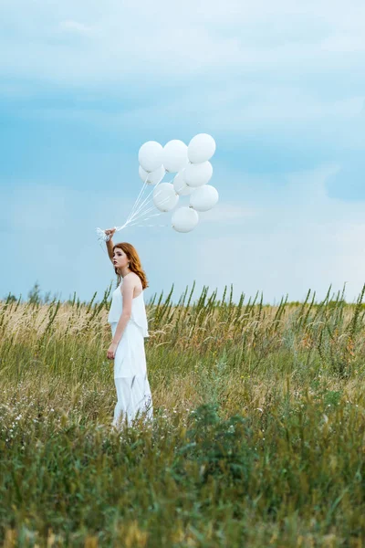 Selektiver Fokus des rothaarigen Mädchens, das Luftballons im Feld hält — Stockfoto
