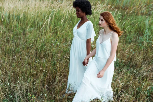 Young and pretty multicultural women walking in green field — Stock Photo