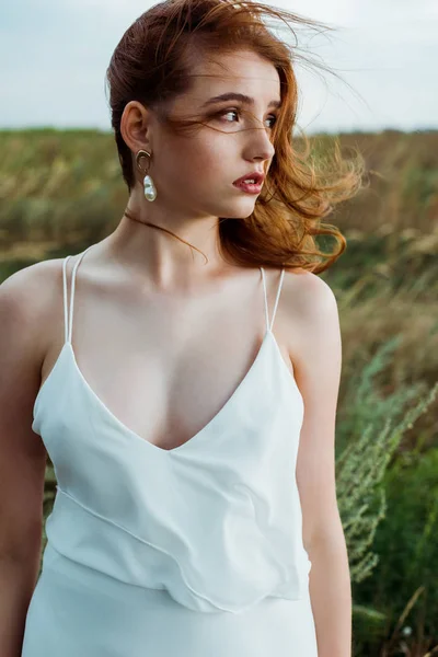 Young and beautiful redhead woman in white dress in field — Stock Photo