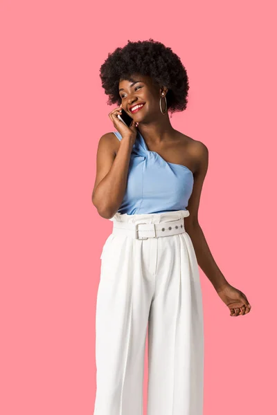 Улыбающаяся африканская американка разговаривающая на смартфоне изолированная на розовом — стоковое фото