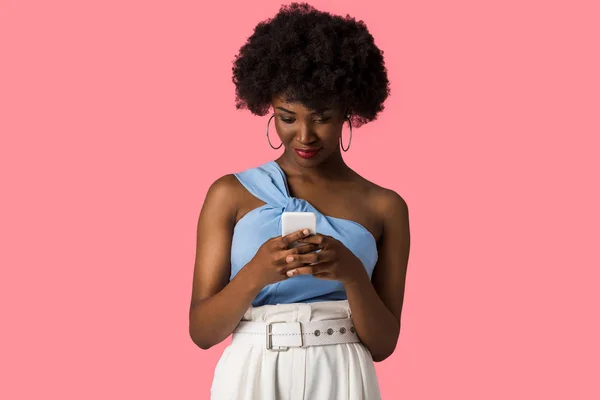 Bella ragazza afroamericana utilizzando smartphone isolato su rosa — Foto stock