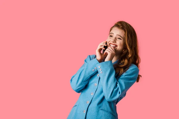 Sonriente pelirroja hablando en smartphone aislado en rosa - foto de stock