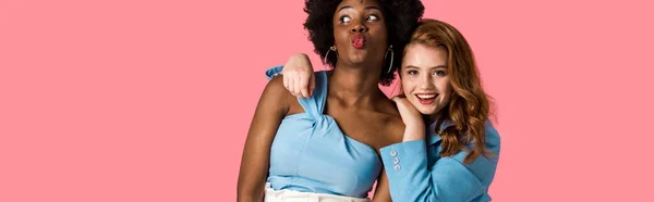 Panoramic shot of happy redhead girl standing near african american with duck face isolated on pink — Stock Photo