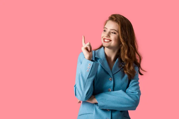 Menina ruiva feliz apontando com o dedo isolado em rosa — Fotografia de Stock