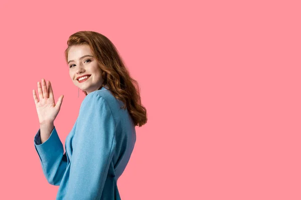 Smiling pretty girl looking at camera while waving hand isolated on pink — Stock Photo