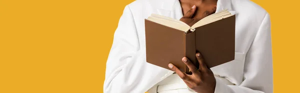 Plano panorámico de mujer afroamericana sosteniendo libro aislado en naranja - foto de stock