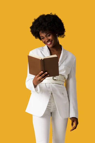 Mujer afroamericana feliz lectura libro aislado en naranja - foto de stock