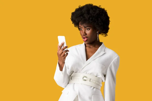 Choqué frisé afro-américain femme regardant smartphone isolé sur orange — Photo de stock