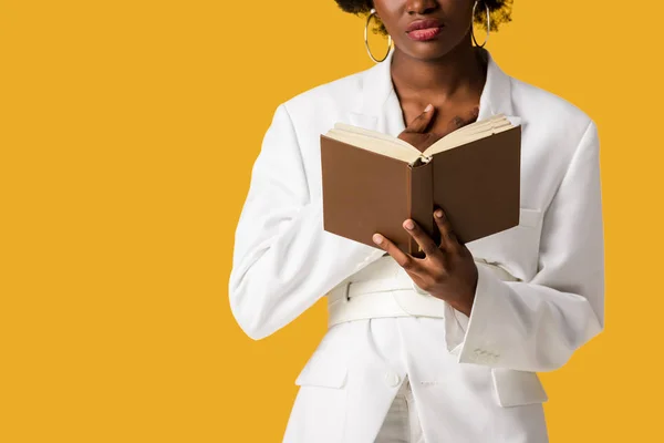 Vista cortada de mulher afro-americana segurando livro isolado em laranja — Fotografia de Stock
