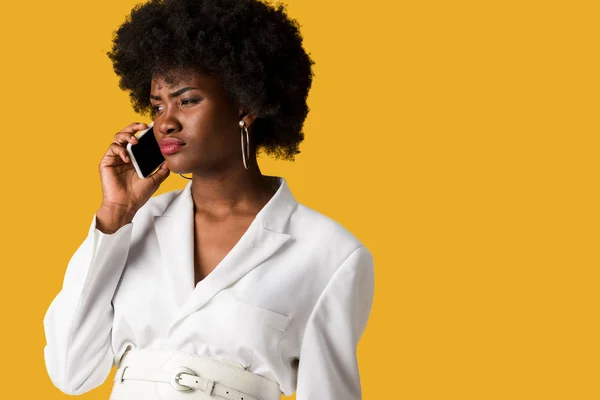 Mujer afroamericana disgustada hablando en teléfono inteligente aislado en naranja - foto de stock