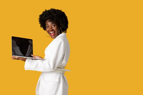 Excité afro-américaine fille tenant ordinateur portable avec écran vide isolé sur orange — Photo de stock