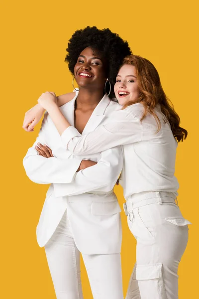 Smiling redhead girl hugging african american woman isolated on orange — Stock Photo