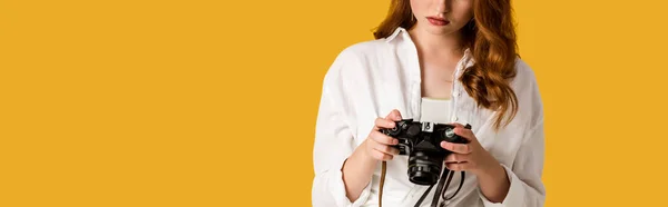 Panoramic shot of redhead girl holding digital camera isolated on orange — Stock Photo