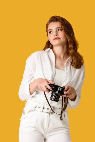 Menina ruiva descontente segurando câmera digital isolada em laranja — Fotografia de Stock