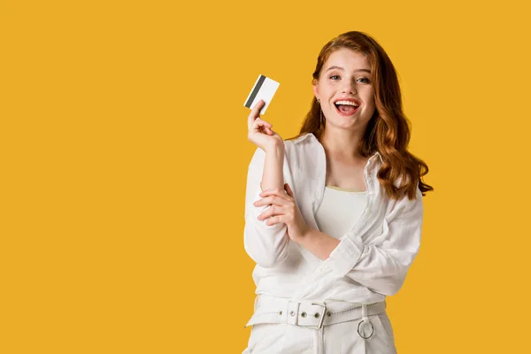 Excited young woman holding credit card isolated on orange — Stock Photo