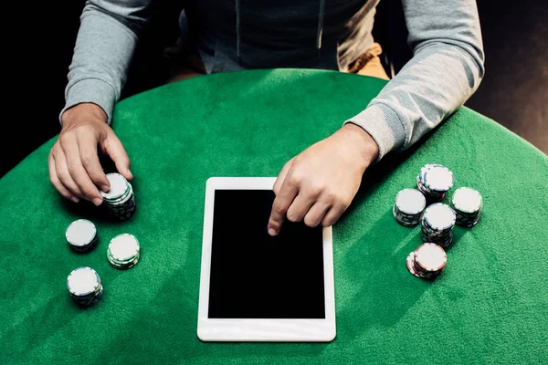 Top view of man pointing with finger at laptop with blank screen near poker chips — Stock Photo