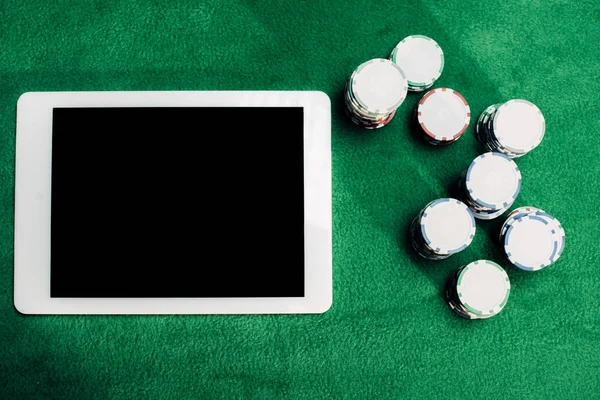 Vue du dessus de la tablette numérique avec écran vierge près des jetons de poker sur la table de poker — Photo de stock