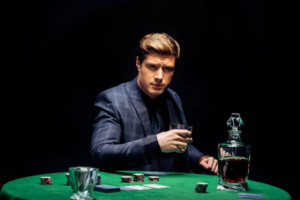 Selective focus of handsome man holding glass with whiskey isolated on black — Stock Photo