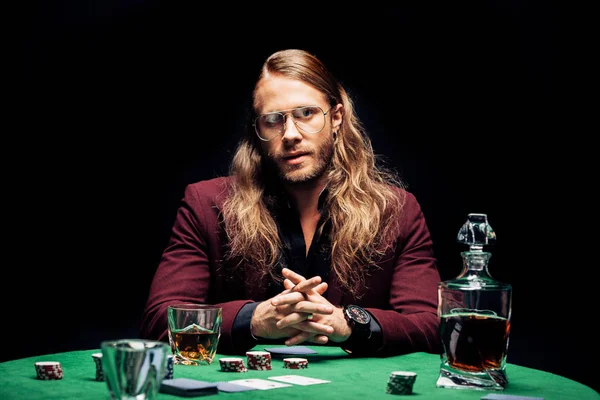 Selektiver Fokus des Mannes in Brillengläsern in der Nähe von Spielkarten am Pokertisch isoliert auf schwarz — Stockfoto
