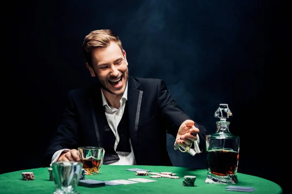 Foyer sélectif de l'homme heureux tenant verre avec de l'alcool sur noir avec de la fumée — Photo de stock