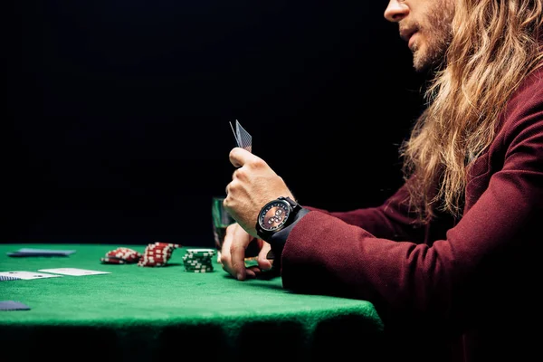 QUIIV, UCRÂNIA - AGOSTO 20, 2019: visão lateral do homem barbudo segurando cartas isoladas em preto — Fotografia de Stock