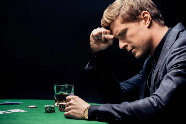 Vista laterale di uomo frustrato giocare a poker isolato su nero — Foto stock