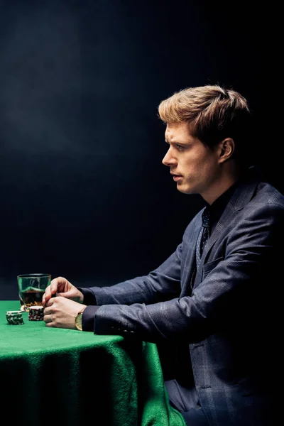 Side view of man playing poker on black with smoke — Stock Photo