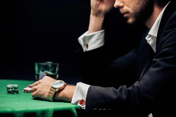 KYIV, UKRAINE - AUGUST 20, 2019: cropped view of bearded man holding playing card isolated on black — Stock Photo