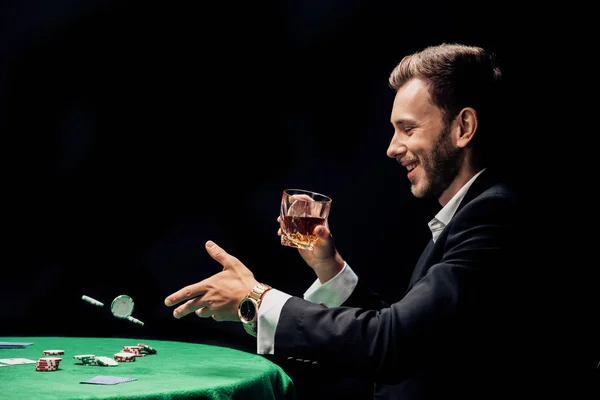 Homem feliz jogando em fichas de poker ar isolado em preto — Fotografia de Stock