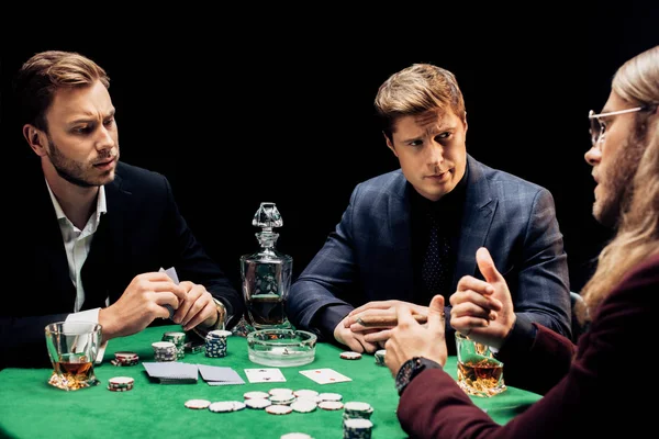 KYIV, UKRAINE - 20 AOÛT 2019 : mise au point sélective des hommes jouant au poker isolé sur noir — Photo de stock