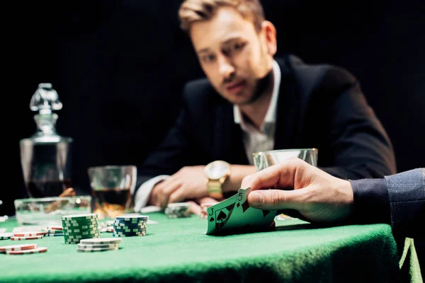 KYIV, UKRAINE - AUGUST 20, 2019: cropped view of man touching playing cards near player isolated on black — Stock Photo