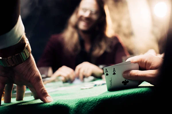 KYIV, UKRAINE - 20 de agosto de 2019: foco seletivo do homem tocando cartas de baralho perto do jogador feliz no preto com fumaça — Fotografia de Stock