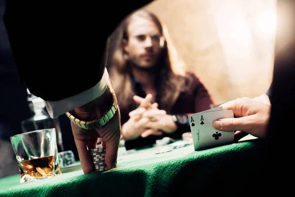 KYIV, UKRAINE - AUGUST 20, 2019: selective focus of man touching playing cards near player on black with smoke — Stock Photo