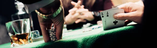 KYIV, UKRAINE - 20 de agosto de 2019: tiro panorâmico de homem tocando cartas de baralho e fichas de poker perto do jogador — Fotografia de Stock