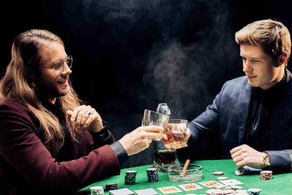 KYIV, UKRAINE - AUGUST 20, 2019: happy men clinking glasses on black with smoke — Stock Photo