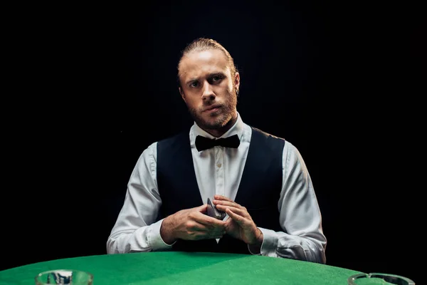 Kyiv, ukraine - 20. August 2019: schöner bärtiger Croupier mit Spielkarten isoliert auf schwarz — Stockfoto