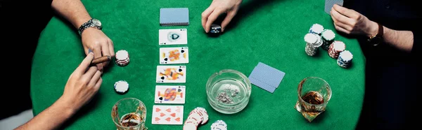 KYIV, UKRAINE - 20 AOÛT 2019 : prise de vue panoramique d'hommes jouant au poker sur table de poker isolés sur noir — Photo de stock