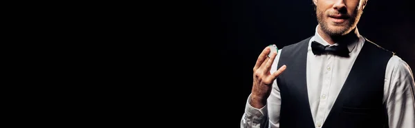 Panoramic shot of bearded man holding poker chip isolated on black — Stock Photo